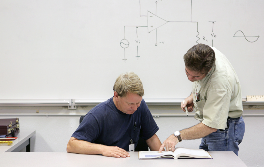 A middle aged adult education student getting help from his teacher.